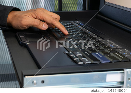 Close up of person pressing keys rugged black laptop keyboard mounted inside metal equipment rack showing hands computer technology for industrial data entry technical operations. Close up of person pressing keys rugged black laptop keyboard mounted inside metal equipment rack showing hands computer technology for industrial data entry technical operations. 143540094