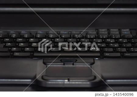 Close up of black laptop keyboard visible letter keys integrated touchpad soft low light highlighting modern computer hardware digital technology everyday office equipment Close up of black laptop keyboard visible letter keys integrated touchpad soft low light highlighting modern computer hardware digital technology everyday office equipment 143540096