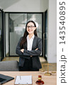 Asian female lawyer in a suit holding a contract in her office. Confident attorney standing by a desk 143540895