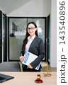Asian female lawyer in a suit holding a contract in her office. Confident attorney standing by a desk 143540896