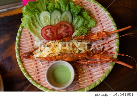 A Deliciously Grilled Lobster Dish Served with Fresh Vegetables and Spicy Dipping Sauce Presented on a Bamboo Platter. A Deliciously Grilled Lobster Dish Served with Fresh Vegetables and Spicy Dipping Sauce Presented on a Bamboo Platter. 143541901