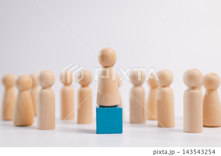 Wooden leader stands on a blue block among a crowd, representing leadership, business management, promotion, career success, confidence, authority, teamwork, influence, and achievement. 143543254