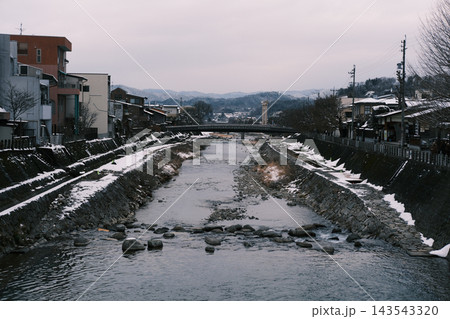 雪の残る川と山あいの町並み 雪の残る川と山あいの町並み 143543320