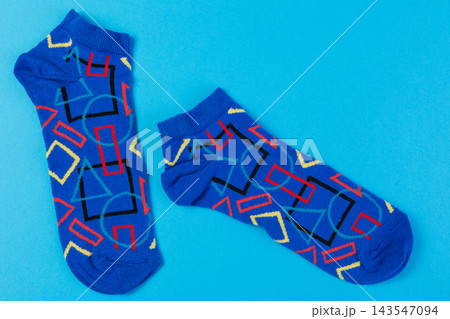 Pair of bright blue ankle socks with colorful geometric abstract pattern on blue background 143547094