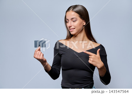 Young woman holding credit card and pointing at it portrait Young woman holding credit card and pointing at it portrait 143547564