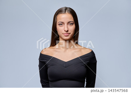 Portrait of confident young woman in off-shoulder black top against grey background Portrait of confident young woman in off-shoulder black top against grey background 143547568