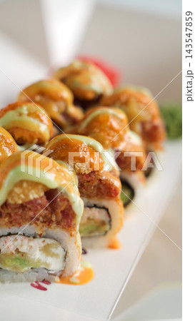 Spicy sushi rolls with tempura and avocado, drizzled with creamy sauces, gourmet Asian food takeaway Spicy sushi rolls with tempura and avocado, drizzled with creamy sauces, gourmet Asian food takeaway 143547859