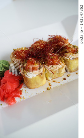 Sushi rolls presenting a gourmet meal, featuring salmon, cream cheese, pistachios, chili threads, and gold flakes 143547862