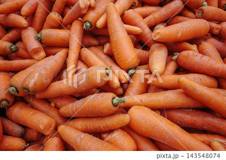 Pile of raw orange carrots with textured skin filling the frame. 143548074