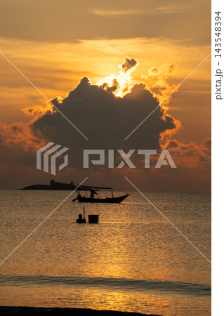 A stunning golden sunset illuminates a calm ocean, creating a dramatic silhouette of a fishing boat and a fisherman. Warm rays peek through clouds, enhancing this peaceful tropical seascape. A stunning golden sunset illuminates a calm ocean, creating a dramatic silhouette of a fishing boat and a fisherman. Warm rays peek through clouds, enhancing this peaceful tropical seascape. 143548394