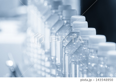 Close up of a row of PET bottles moving on a conveyor belt in a light blue scene Close up of a row of PET bottles moving on a conveyor belt in a light blue scene 143548950