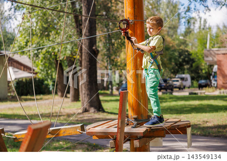 Boy wearing safety harness on ropes course in outdoor adventure park Boy wearing safety harness on ropes course in outdoor adventure park 143549134