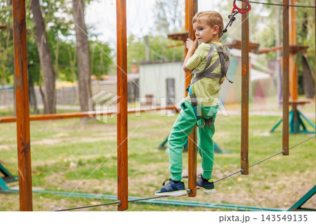 Boy climbing rope course in outdoor adventure park Boy climbing rope course in outdoor adventure park 143549135