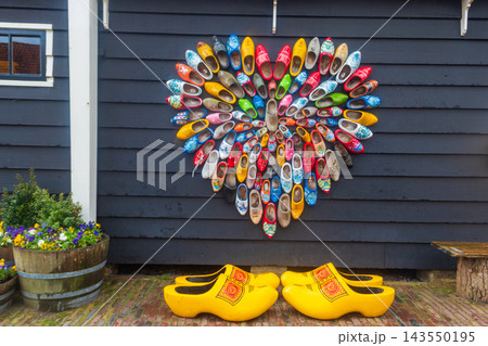 Heart composition made from traditional Dutch wooden clogs on a house wall with giant yellow footwear on display in Zaanse Schans, Zaandam, Netherlands 143550195