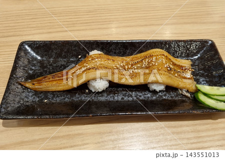 Grilled Anago Sushi, Long Conger Eel Nigiri with Sweet Tare Sauce and Sesame on Black Plate, Japanese Food 143551013