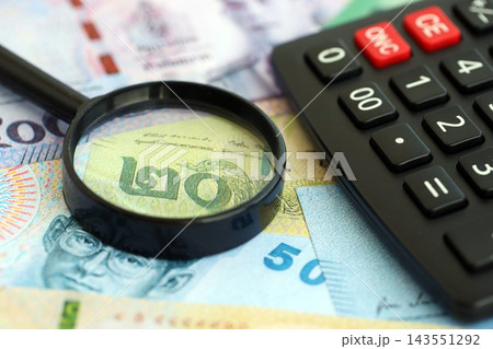 Thai baht currency money bills and calculator with magnifying glass. The concept of taxation Thai baht currency money bills and calculator with magnifying glass. The concept of taxation 143551292