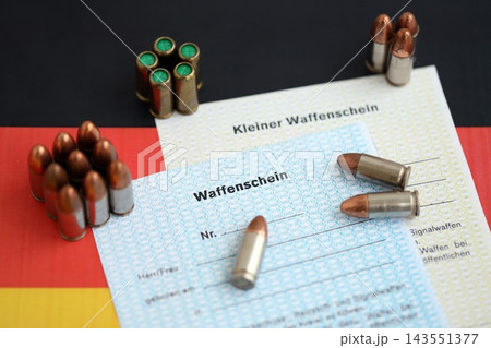 German firearms licenses and bullets on Germany flag close up. Gun permit for weapon carrying 143551377