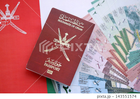 Omani passport and money on flag. Official identification document book for citizens of Oman Omani passport and money on flag. Official identification document book for citizens of Oman 143551574
