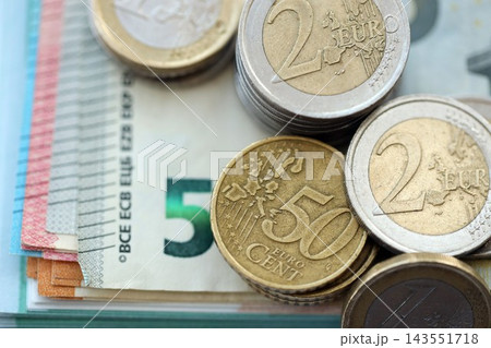 Eurozone euro money bills and cent coins pile on table. Eurozone coins on banknotes of EUR currency Eurozone euro money bills and cent coins pile on table. Eurozone coins on banknotes of EUR currency 143551718