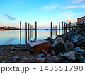 Old Wooden Pilings and Rocks Under Blue Sky 143551790