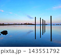 Weathered Wooden Posts Standing in Still Blue Water 143551792