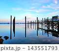 Wooden Dock and Pilings Reflected in Calm Water at Dawn 143551793