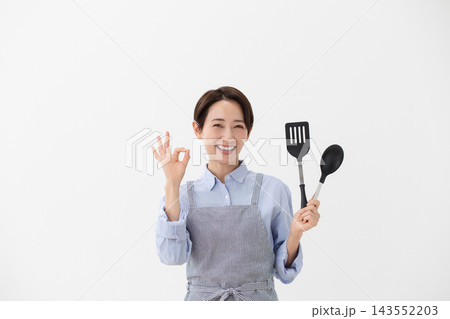 左手にターナーとスパチュラを持つ女性の料理イメージ 左手にターナーとスパチュラを持つ女性の料理イメージ 143552203