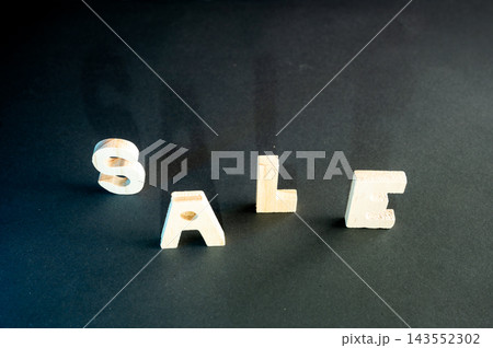 Minimal SALE Concept on a Dark Background. Wooden letters spelling SALE on a dark moody background with soft colorful lighting, a creative conceptual image of discounts, bargains and seasonal shopping Minimal SALE Concept on a Dark Background. Wooden letters spelling SALE on a dark moody background with soft colorful lighting, a creative conceptual image of discounts, bargains and seasonal shopping 143552302