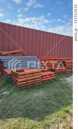 Agricultural storage yard showing irrigation supply pipes and greenhouse packaging containers, farm operation setup Agricultural storage yard showing irrigation supply pipes and greenhouse packaging containers, farm operation setup 143552610