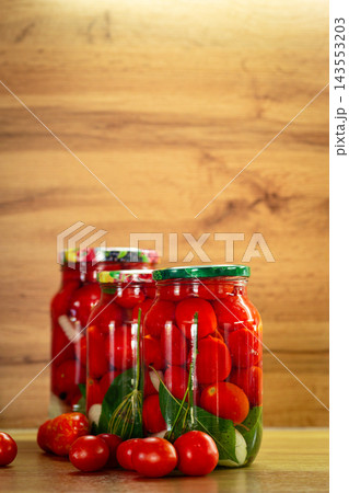 Traditional pickled tomatoes with dill and garlic in glass jars Traditional pickled tomatoes with dill and garlic in glass jars 143553203