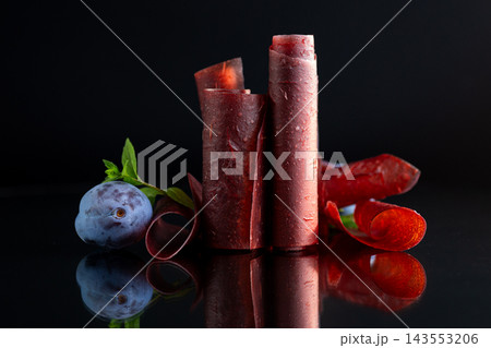 Natural dried plum pastila with fresh plums on black surface Natural dried plum pastila with fresh plums on black surface 143553206