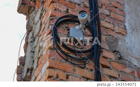 Security surveillance camera and wiring mounted on old brick building wall 143554071