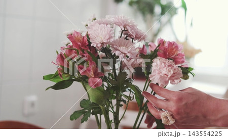 Pink bouquet on a festive table with a hand reaching in. Celebration and attention. Pink bouquet on a festive table with a hand reaching in. Celebration and attention. 143554225