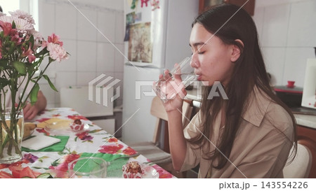 Teenage girl drinking water at a festive table. Fresh morning and healthy habits. 143554226