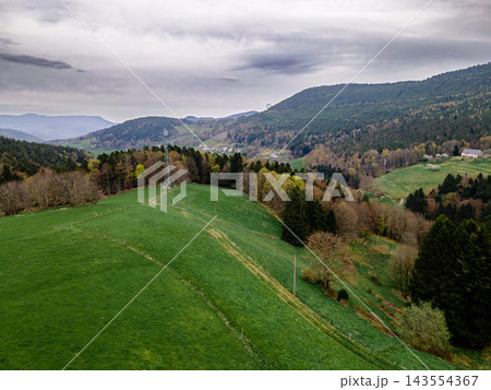Rolling green hill with winding path and mountain overlook. Rolling green hill with winding hiking path leading to tranquil mountain overlook, aerial view of spring meadow trail with distant peaks on  143554367