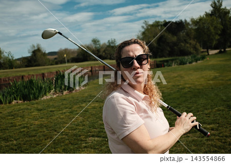 Middle aged woman playing golf on a green golf course outdoors Middle aged woman playing golf on a green golf course outdoors 143554866