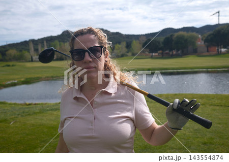 Middle aged woman playing golf on a green golf course outdoors 143554874