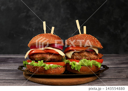 Two double cheeseburgers with fresh lettuce, tomato, cream cheese, chili peppers, bacon, onion, and a patty on a wooden tray, food delivery concept, menu and advertising for cafes and restaurants, Two double cheeseburgers with fresh lettuce, tomato, cream cheese, chili peppers, bacon, onion, and a patty on a wooden tray, food delivery concept, menu and advertising for cafes and restaurants, 143554880