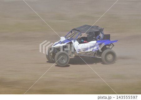 砂埃が舞うダートコースを疾走する青と白のバギーカー 143555597