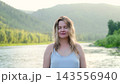 Beautiful young woman relaxing and enjoying the sunset. Portrait of a girl against the backdrop of summer nature. Pretty happy lady enjoying summer outdoors. Positive emotions, life success, peace 143556940