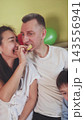 Husband eating a chip from his wife's hand. Playful love, trust and family humor. 143556941