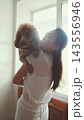 Woman holding a fluffy poodle close to her face. Love, tenderness and pet therapy. 143556946