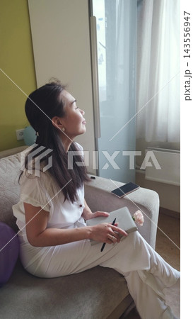 Thoughtful woman looking away from her journal. Inspiration, dreams and inner dialogue. 143556947
