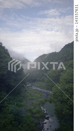 緑豊かな山肌と白い霧が織りなす奥多摩渓谷の縦位置風景 143557631