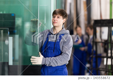 Guy glazer employee in blue overall works in glass processing shop 143558672