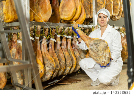 In jamon production shop, woman employee demonstrates final product 143558685