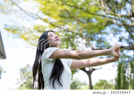 Asian Woman Stretching Arms Forward with Closed Eyes in Nature 143559447
