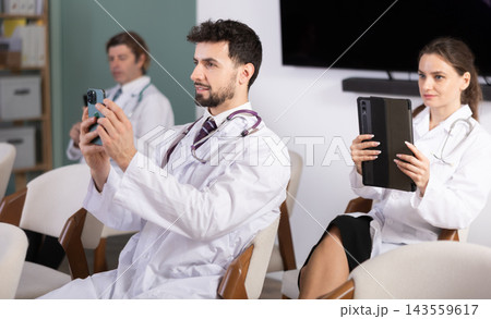 Medical students or doctors using mobile phones to scan QR-code during interactive lesson Medical students or doctors using mobile phones to scan QR-code during interactive lesson 143559617