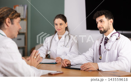 Representatives of medical professional community sitting at table and chatting Representatives of medical professional community sitting at table and chatting 143559618