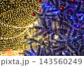 Christmas tree pine branches decorated with red ornaments and glowing fairy lights background 143560249